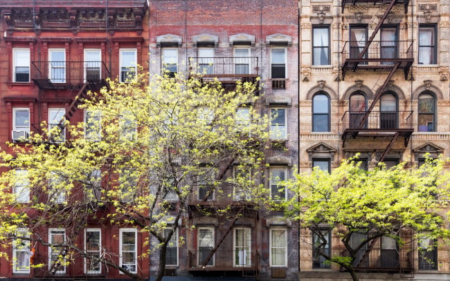 a row of new york city apartments with trees in front.